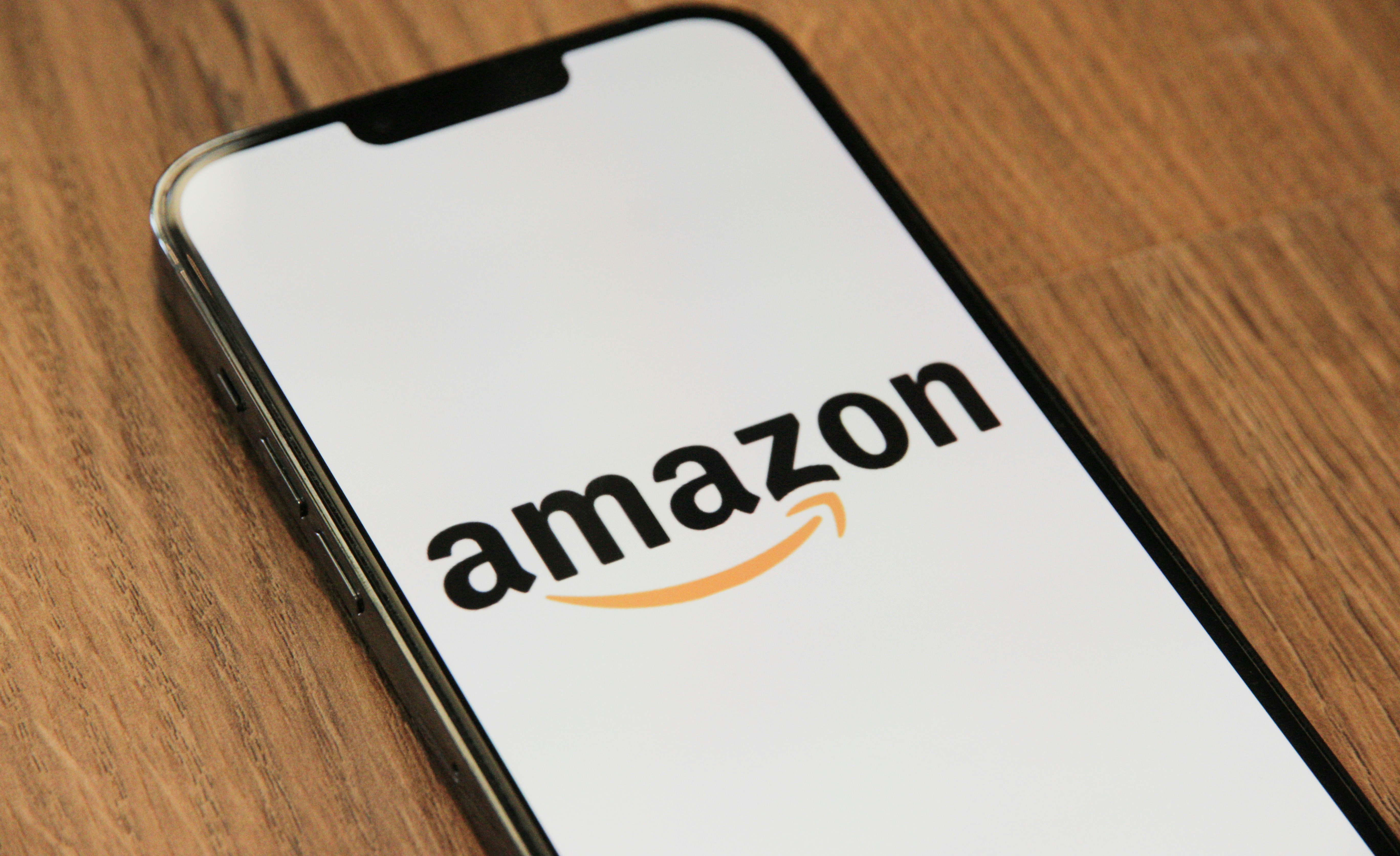 Smartphone displaying the Amazon logo on a wooden table