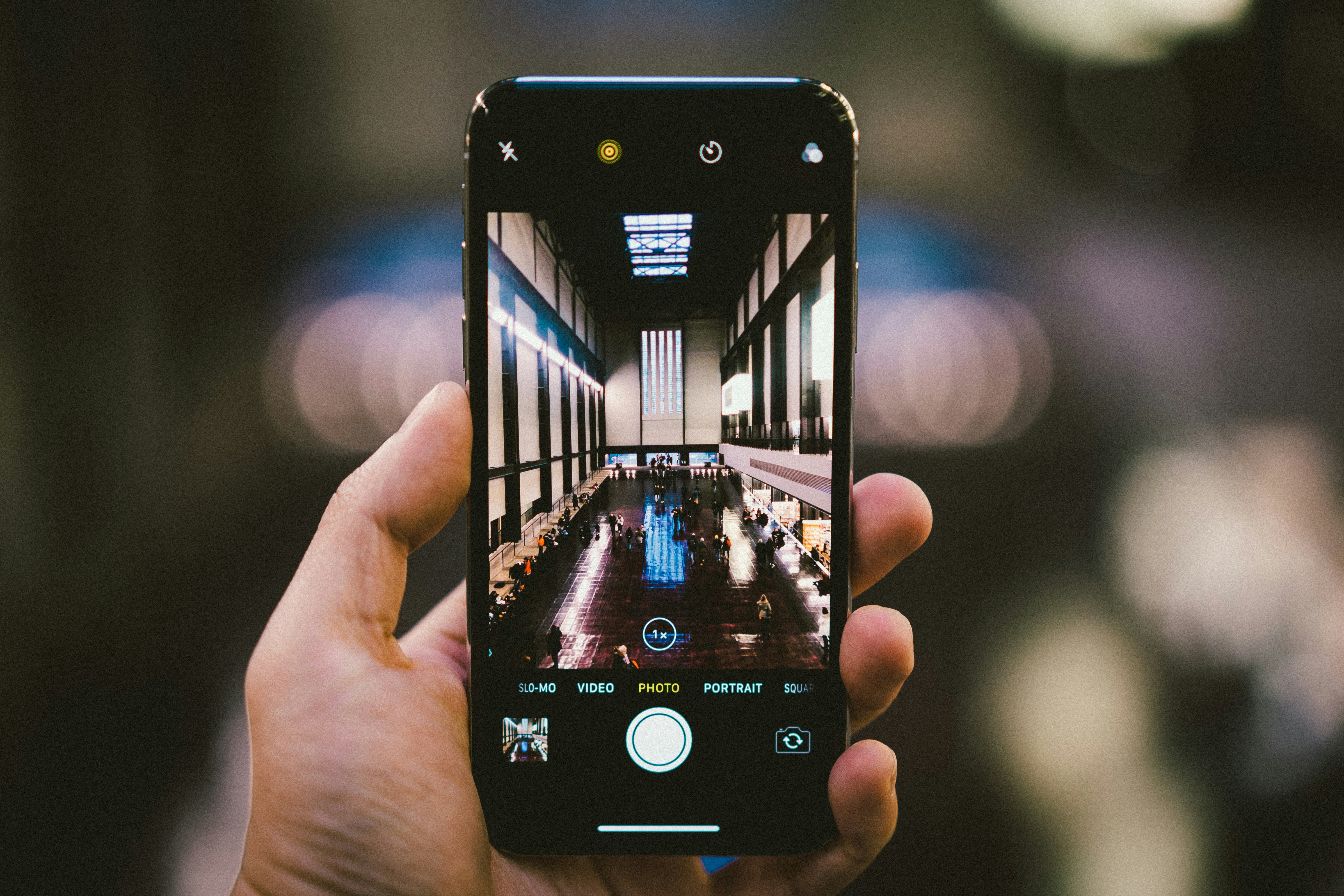 Hand holding a smartphone taking a photo inside a gallery hall